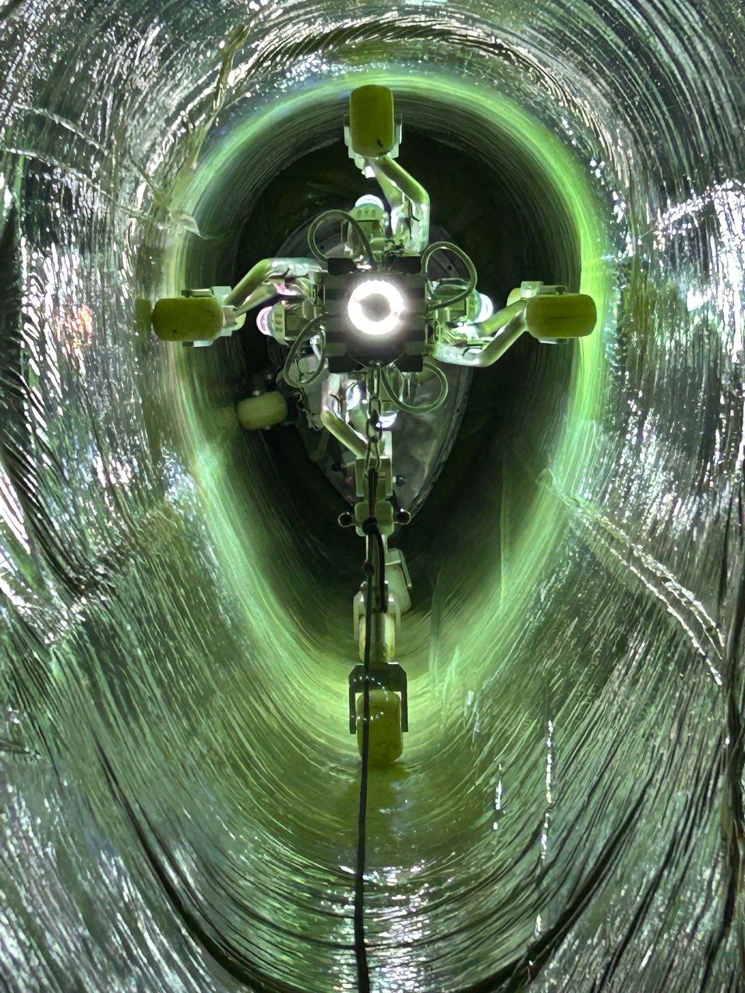 UV curing inside relined oviform pipe — green UV light visible