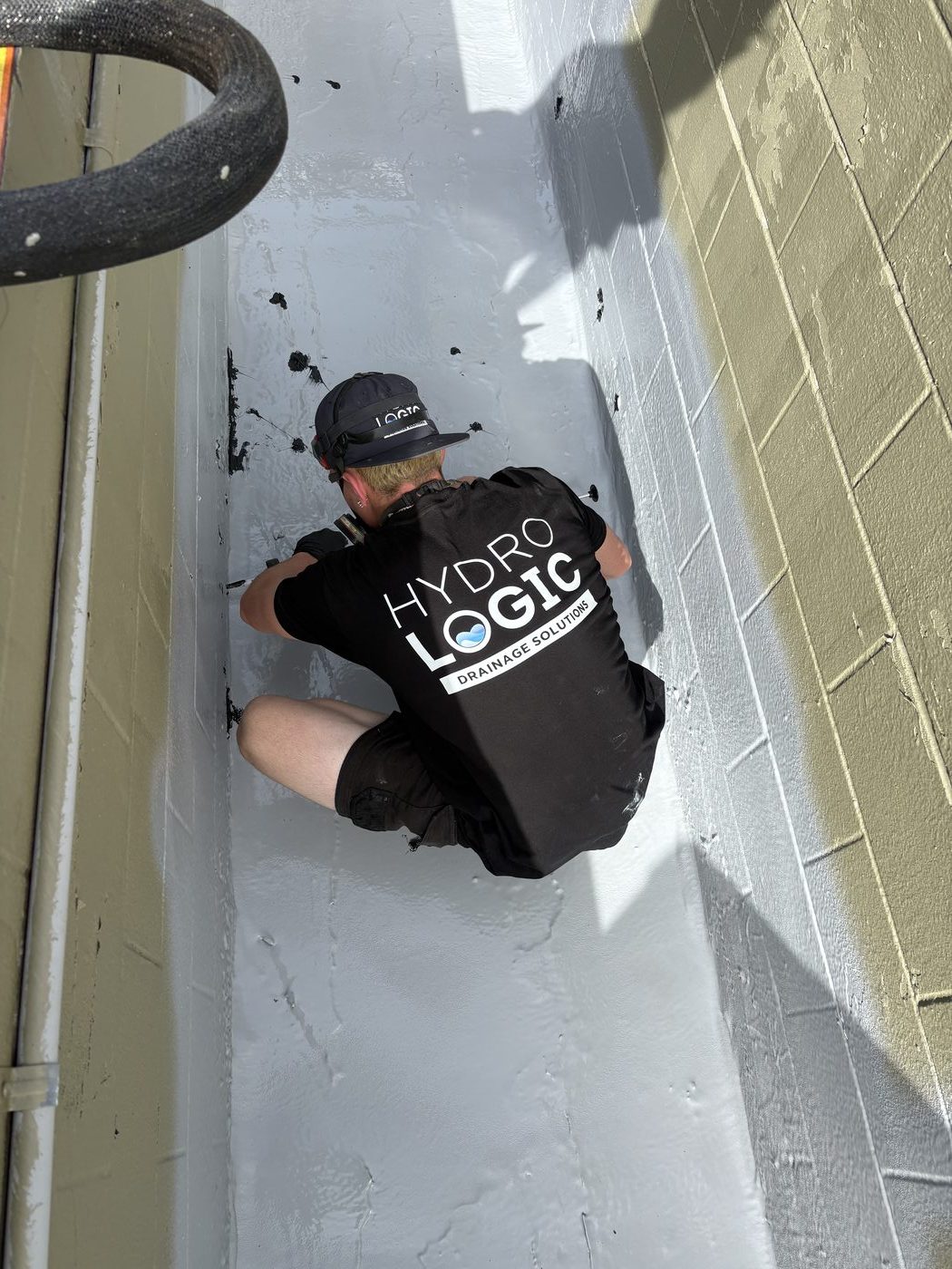 Hydro Logic technician spray-applying a protective membrane inside a commercial planter box