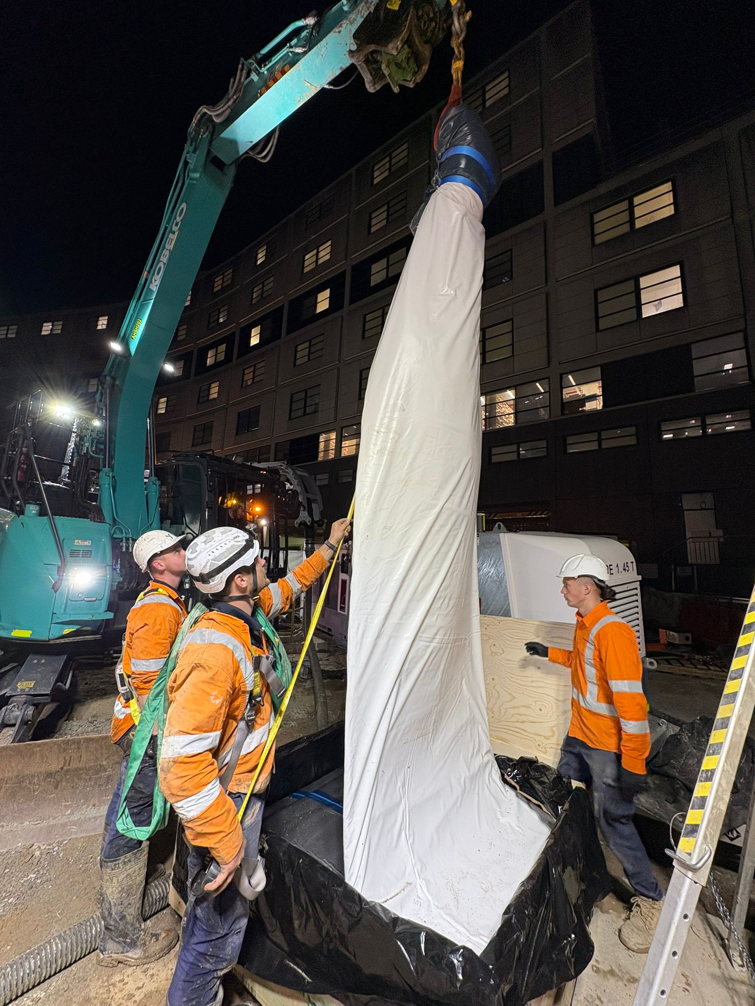 Tier-1 construction — pipe relining night works with crane and hi-vis crew